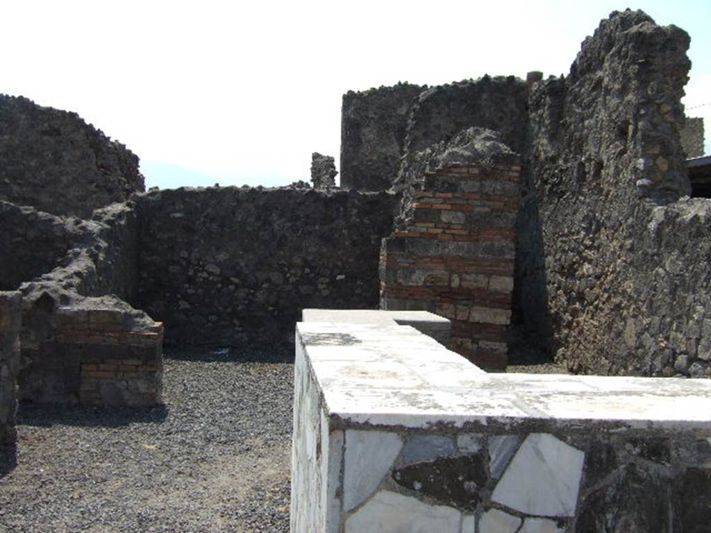VI.4.1 Pompeii. May 2006. Looking south across counter towards rear room, and small room, on the right, possibly a latrine.
