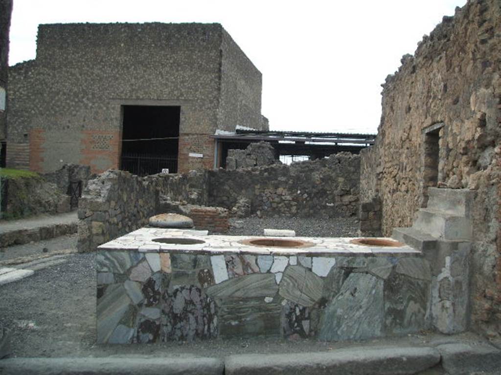 VI.4.8 Pompeii. December 2006. Sales counter, looking west to rear room. 
The entrance, VI.4.9 on Via delle Terme, can be seen on the south (left) side. According to Garcia y Garcia, this area was nearly all destroyed by the bombing in 1943. The bomb provoked the total fall of the walls, internal and external onto Via Consolare, between the north wall and on its east side.
See Garcia y Garcia, L., 2006. Danni di guerra a Pompei. Rome: L�Erma di Bretschneider. (p.75)
