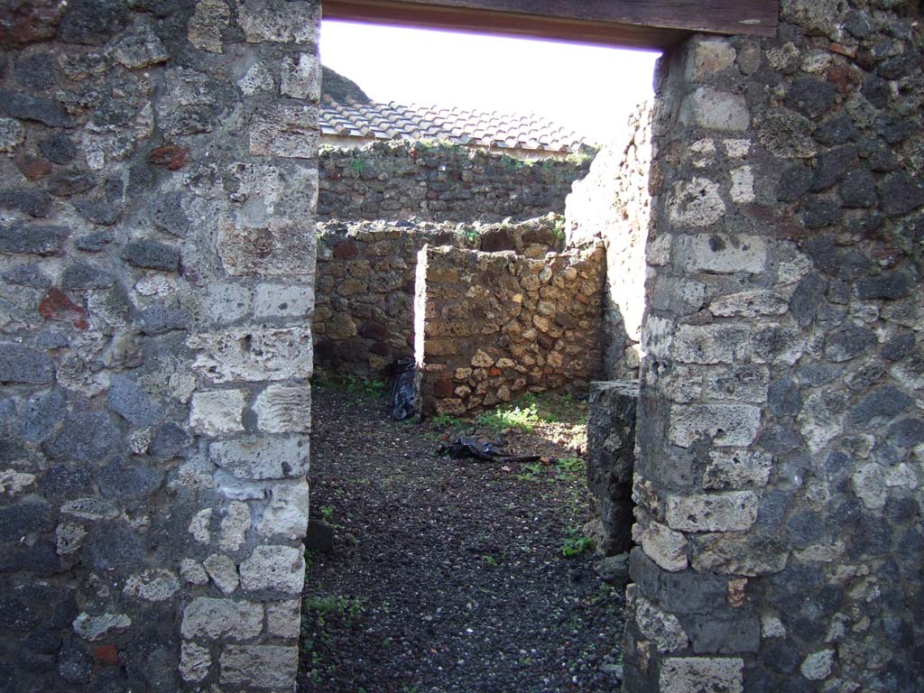 VI.5.14 Pompeii. December 2005. Looking west through doorway into kitchen area
The walls of the latrine can be seen in north-west corner.
The north-west corner of this room, the latrine, shows that today there is no doorway of VI.5.11 here, as shown on Eschebach plan.
VI.5.11, steps to an independent upper floor, is now to the north of this corner, fronting onto Vicolo di Modesto, and is completely separate from here.

According to CTP, the north-west corner of the house at VI.5.14 was excavated in 1817, as well as the pseudoperistyle of VI.5.10 and atrium area of VI.5.9.
The street wall at the north-west corner of the house at VI.5.14 collapsed and was reconstructed, which may provide the reason why Tascone, Mau and Eschebach, all indicated a rear doorway of this house immediately south of the stairway, which, rightfully should be assigned a number. 
The doorway is delineated by Russo’s map of 1817, and later by Mazois, Fiorelli – Sorgente, and Zangemeister (1865). 
Today the number VI.5.11 is not in situ but it has been assigned by the SANP to the staircase. 
See Van der Poel, H. B., 1981. Corpus Topographicum Pompeianum, Part V. Austin: University of Texas. (p.196-7)
