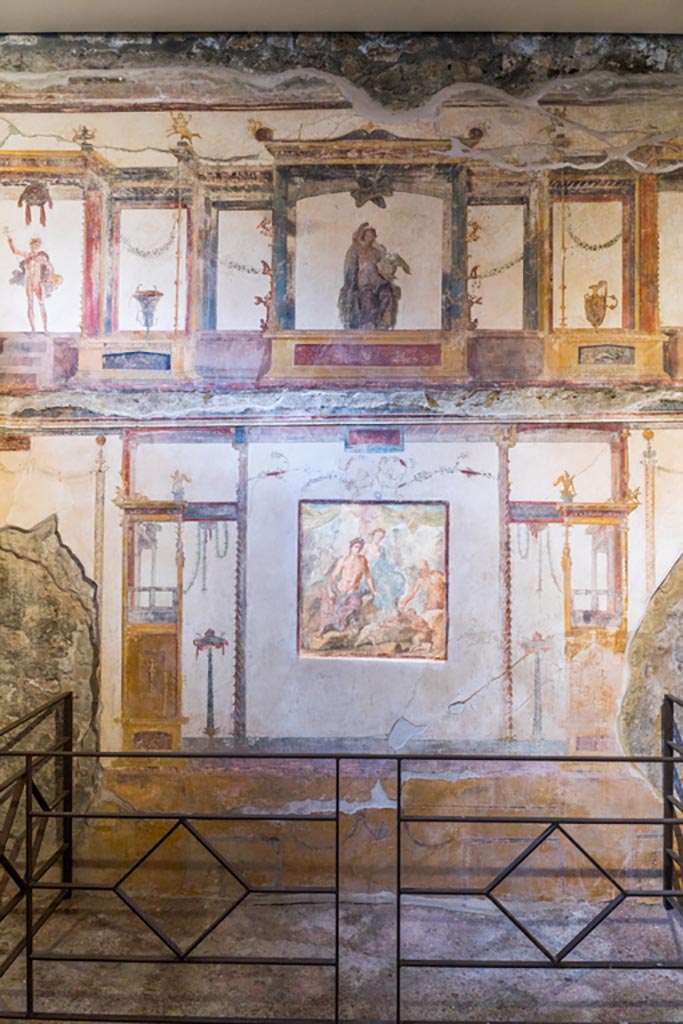 VI.15.1 Pompeii. March 2023.
Looking towards central panel of south wall with painting showing fight between Eros and Pan.
In the upper centre is a painted aedicula containing Leda and the swan. Photo courtesy of Johannes Eber.