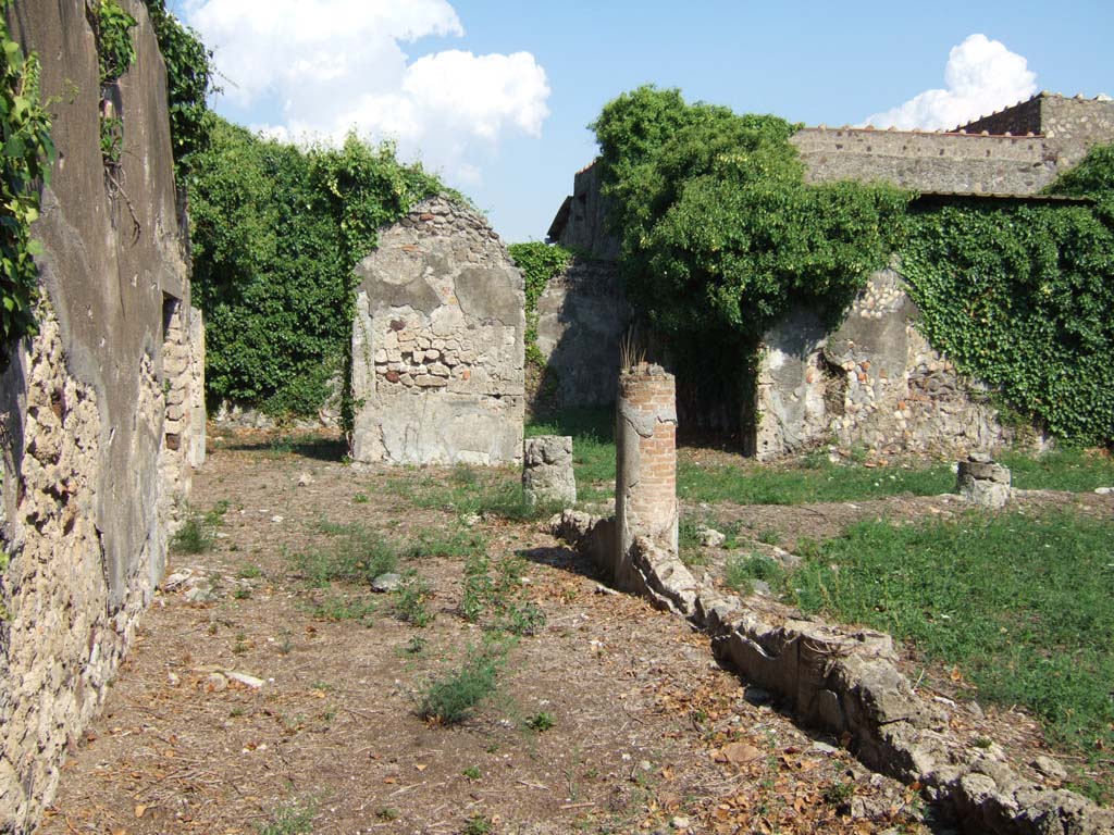 VI.15.23 Pompeii. September 2005. Looking east along north portico towards pilaster.
According to Sogliano, two paintings were discovered on the pilaster between the oecus and tablinum/triclinium on the east portico.
Both paintings had a black background and preserved around them was an unequal margin of red plaster that was on the wall from which they were removed.
On the lower right corner of the photograph, (fig.2 below), an iron nail-head can be seen, with another in the middle of the lowest margin.
These paintings were cut from the wall and taken to Naples Archaeological Museum.
See Notizie degli Scavi di Antichità, 1897, p. 154-5.
