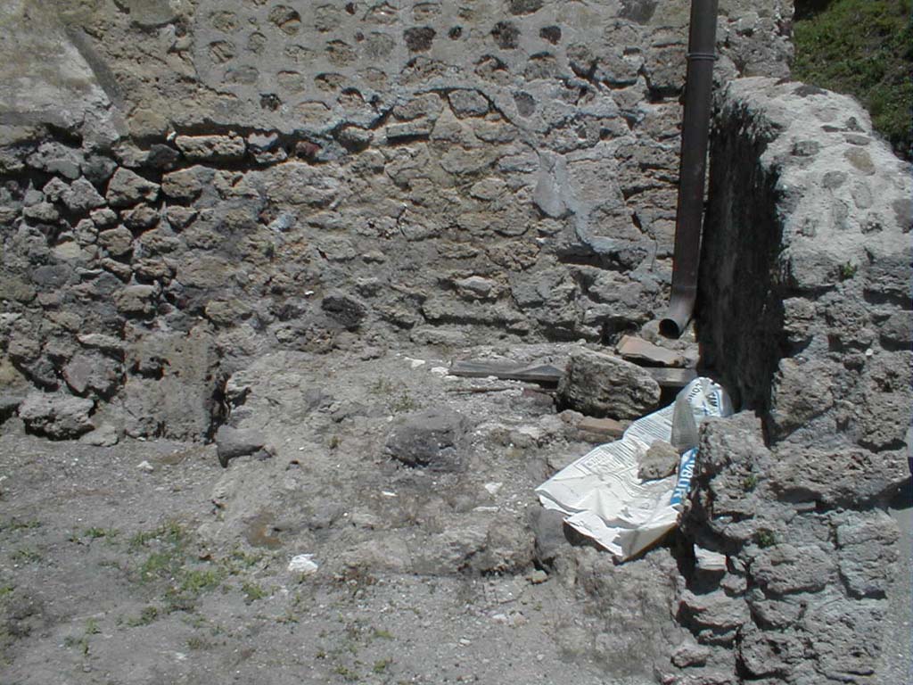 VI.16.6 Pompeii. May 2005. North-east corner of fullonica, with structure, possibly remains of tub or basin.
According to Sogliano, the walls were undecorated at the bottom to the height of the dado, and then above were crudely painted in white. 
Leaning against the north wall would have been a wooden ladder, which probably led up to some rooms at the top of the House of the Golden Cupids. 
Also against the north wall were a masonry structure with two steps. 
To left were the remains of three low walls, arranged like fullonica tanks for treading pigment into cloth. 
There were also the remains of a shallow tank. 
See Notizie degli Scavi di Antichità, 1906, p. 350.
