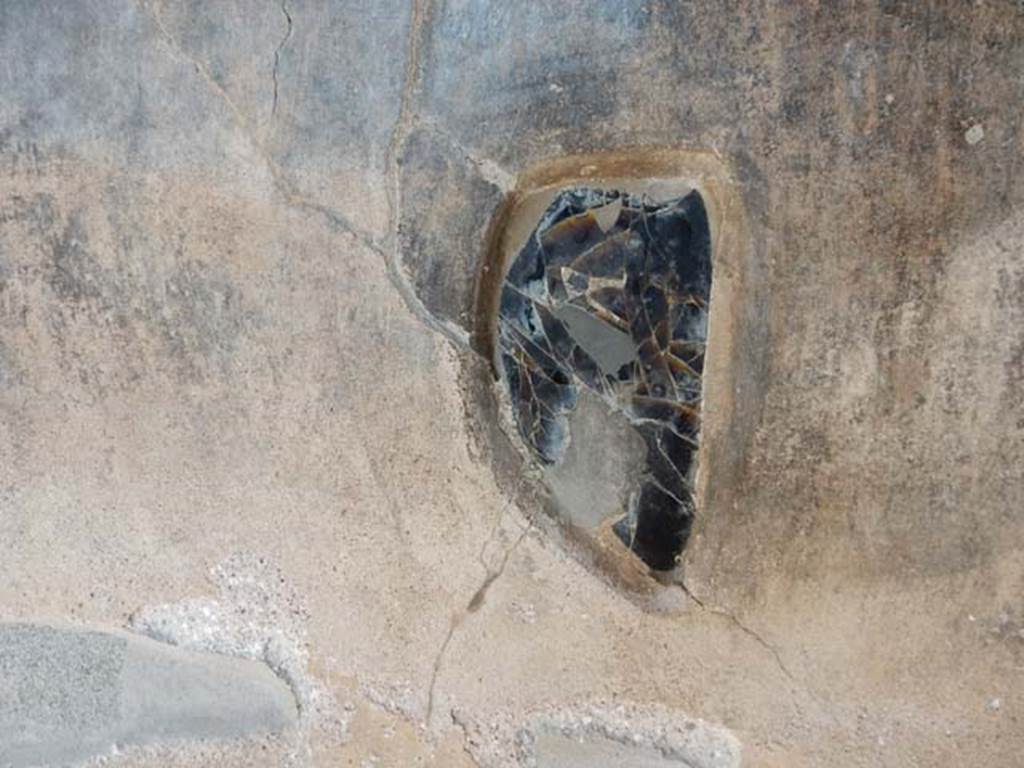 VI.16.7 Pompeii. May 2016. Peristyle F, east wall of east portico at the southern end between the shallow space and the lararium. An obsidian mirror was embedded in the plaster. Photo courtesy of Buzz Ferebee.
