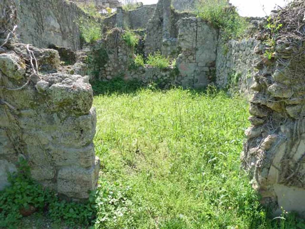 VI.16.11 Pompeii. May 2010. Doorway to rear room in north-west corner of shop. Looking west. According to NdS, the doorway would have had doorjambs and a threshold of wood.
The floor was made of opus signinum but was poorly preserved. The walls were divided into large red panels, divided by yellow pilasters or fillets, with feeding birds in the middle, a flying swan, and a rectangular painting with faded representation. The dado was red but also badly preserved. The frieze had a white background. The remains of the white frieze were still visible upon excavation, in the height of the west wall, in which there was a window. See Notizie degli Scavi di Antichit�, 1908, p. 59.
