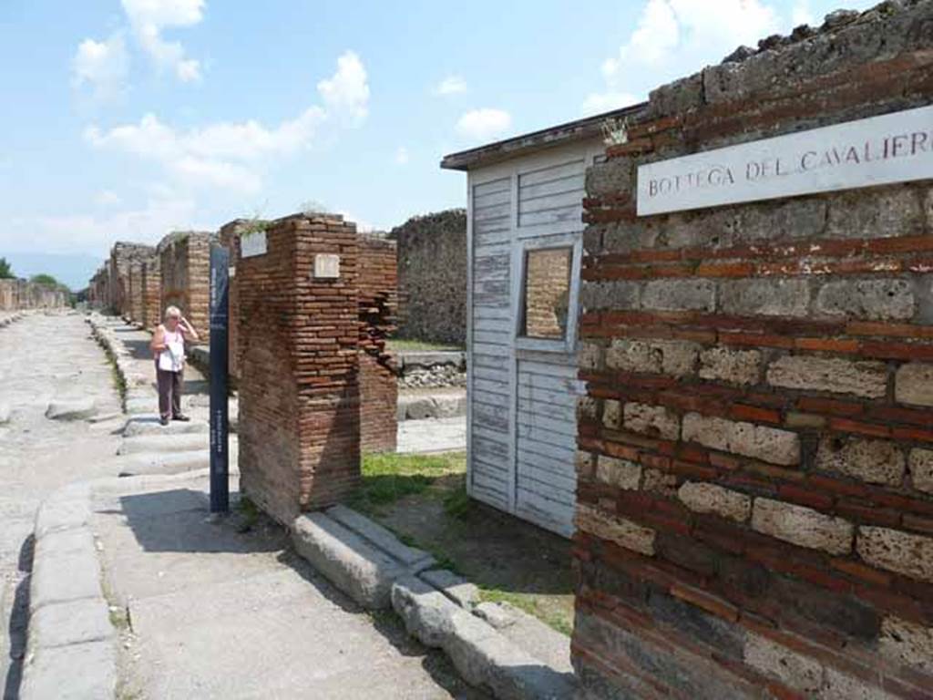 VII.3.14 Pompeii. May 2010. Entrance to shop, looking east across Via Stabiana towards Via di Nola with Bottega del Cavalieri sign.

The tavern (VII, 3, 14-15) was one of the stops of the visit of Pope Pius IX on October 22, 1849, and from where was found, together with a lot of bronze materials and marble fragments, the bas-relief of the galloping cavalier (Museo Profano, Bib. Apostolica Vaticana, inv. 4092), of which there has been much debate about its true Pompeian origin, in a controversy that does not even seem settled after the study made by Conticello (AA.VV., 1987: 31-38, tav. 2) for the catalog of the exhibition twenty years ago dedicated to this visit.
See Uroz S�ez J., Uroz Rodr�guez H., 2008. Pompeya: Regio VII, Insula 3. Instituto del Patrimonio Cultural de Espa�a, p. 60.
