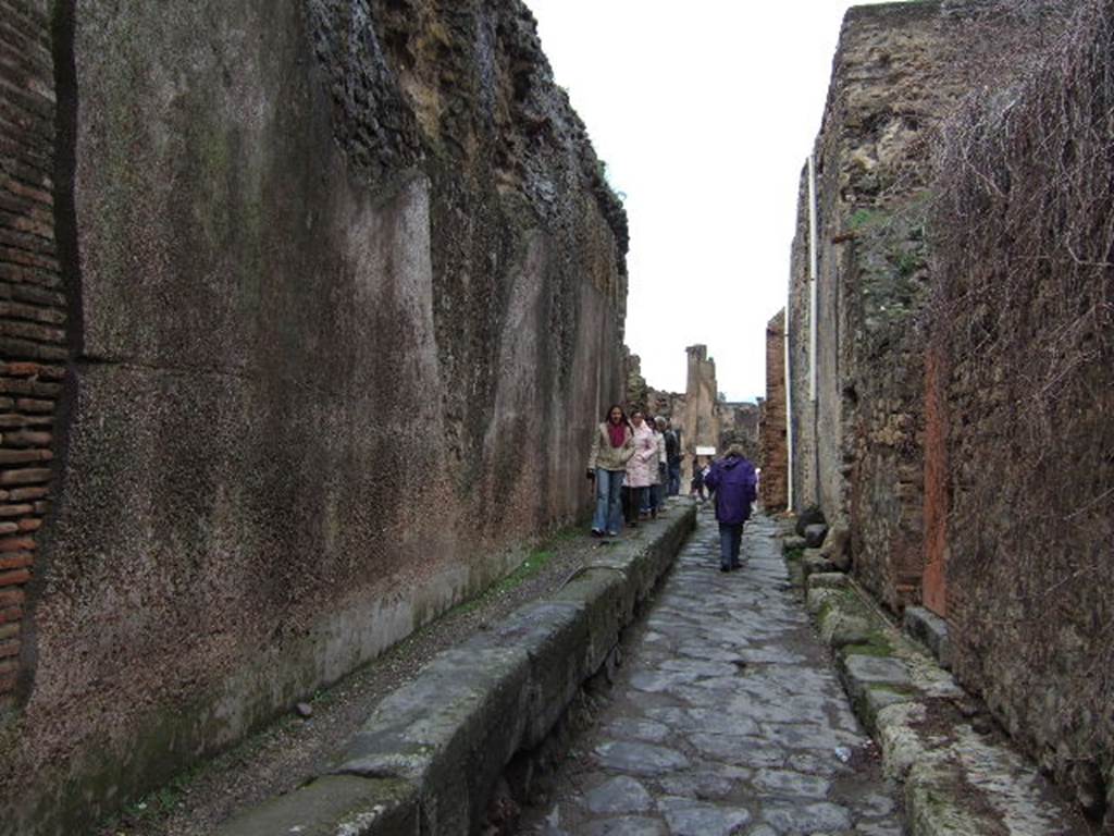 VII.6.17 Pompeii on the left. December 2006. Vicolo delle Terme looking north with VII.5 and Forum baths on the right. Between VII.6.16 and VII.6.17 are three large water storage reservoirs that feed the Forum Baths. These are behind the wall on the left. The tanks were 5m by 15m at the base and 9m high at the top of the curved roof. It is estimated the reservoirs held 430,000 litres of water. See Eschebach, L., 1993. Geb�udeverzeichnis und Stadtplan der antiken Stadt Pompeji. K�ln: B�hlau. (p. 41).