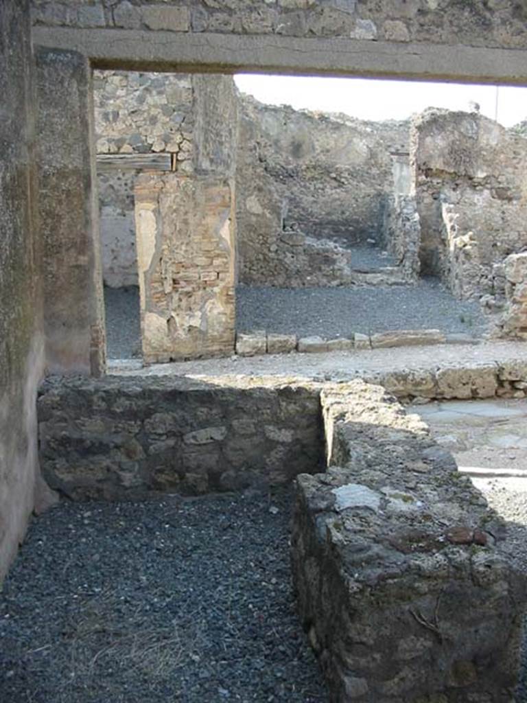 VII.7.18 Pompeii. May 2003. 
Looking north across rear of counter with hearth, towards VII.6.33, opposite on Vicolo dei Soprastanti. 
Photo courtesy of Nicolas Monteix.

