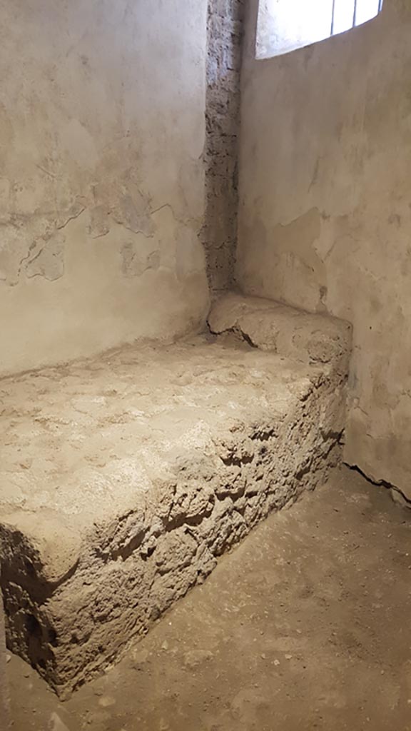 VII.12.8 Pompeii. August 2023.
Stone bed and pillow in room for prostitute. Photo courtesy of Maribel Velasco.