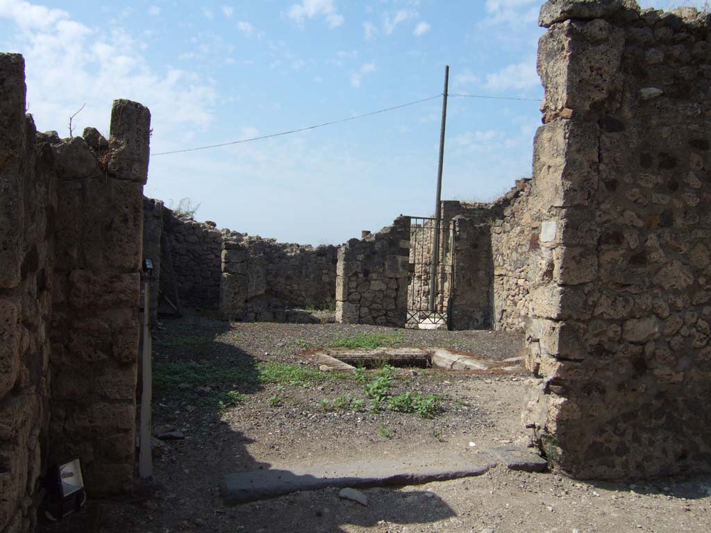 VII.16.12 Pompeii. September 2005. Entrance doorway, looking west.
According to Fiorelli –
“Piccola casetta posta in comunicazione con quella seguente, piu nobile ed antica, ed alla quale serviva forse di uscita secondaria l’ampia porta, che introduce in un atrio tuscanico, con impluvio e due bocche di cisterna di pietra vesuviana, sulla cui parete meridionale era graffito. 
Di fronte stanno due cubicoli, ed accosto una fauce, che menando a stanze sottoposte, teneva a sinistra altre celle, e a destra comunicava con la casa attigua.”
See Pappalardo, U., 2001. La Descrizione di Pompei per Giuseppe Fiorelli (1875). Napoli: Massa Editore. (p.161).
(translation:  "Small house placed in communication with the next following one, more noble and ancient, and to which perhaps the wide doorway was used as a secondary exit, which leads into a Tuscan atrium, with impluvium and two cistern-mouths of Vesuvian stone, on the south wall of which was a graffito (see page 161). 
Facing were two cubicula, and nearby a corridor which leads to the underneath rooms, having other rooms to the left, and on the right communicating with the adjoining house.")
