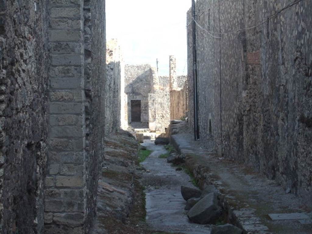 VII.6 Pompeii. September 2005. Vicolo del Farmacista, looking south.    VII.16 on right.  According to Garcia y Garcia, in 1943 the internal unexcavated area between VII.16. A and B (20 and 21) along the Vicolo del Farmacista was hit by a bomb. It fell on the soil not yet excavated and demolished the perimeter wall for a length of 4m x 3m and a part of the escarpment in two areas for 8 metres..
See Garcia y Garcia, L., 2006. Danni di guerra a Pompei. Rome: L�Erma di Bretschneider. (p.137)
