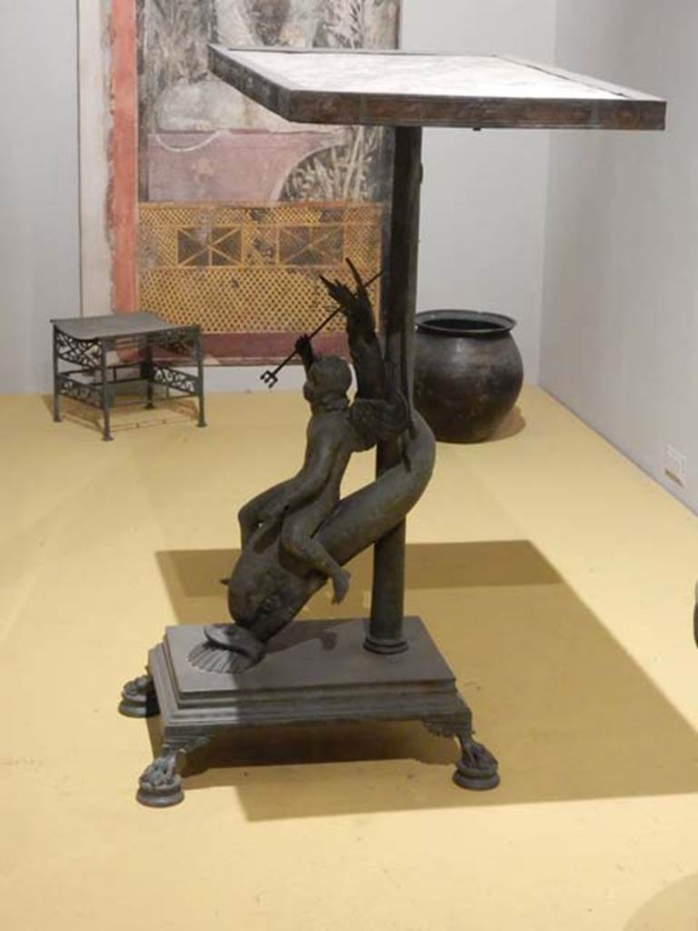 VII.16.17-22, Pompeii. May 2018. 
Bronze stool decorated with palms and lotus flowers. Archaeological Park of Pompeii, inv. 13355.
and Pot (olla) in bronze for the boiling of foods, Archaeological Park of Pompeii, inv. 14069.  
And Table in bronze and marble decorated with a cupid riding a dolphin, Archaeological Park of Pompeii, inv. 13371   .  
Photo courtesy of Buzz Ferebee.
