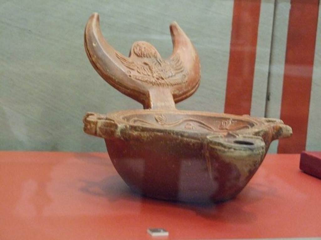 VI.16.19 Pompeii.  Terracotta triple lamp with a crescent moon handle. The handle is decorated with the head of Jupiter Ammon and an eagle. SAP 13961. Photographed at “A Day in Pompeii” exhibition at Melbourne Museum.  September 2009.