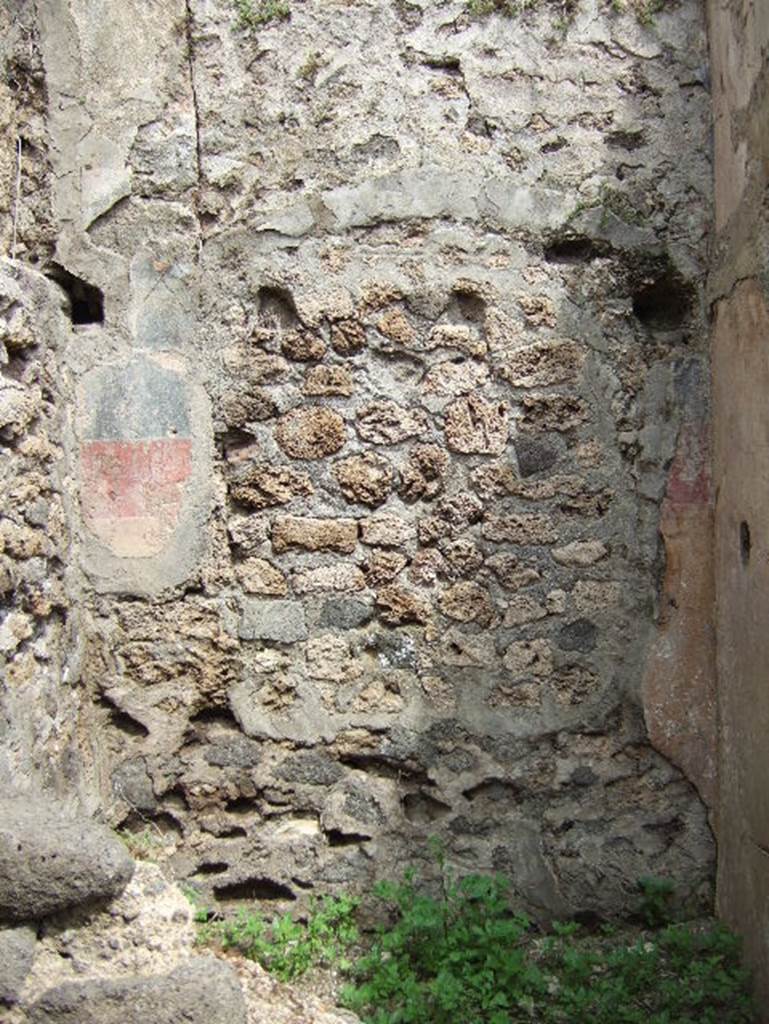 VIII.2.34 Pompeii. May 2006. Room ‘1’, north wall of cubiculum of lower rear room, painted with a high yellow zoccolo, separated from the black painted middle zone by a red line.
Above were the remains of the holes for the beams for the support of a wooden mezzanine.
At the north end of the west wall, the recess for the bed could be seen on the higher level (top left of photo).