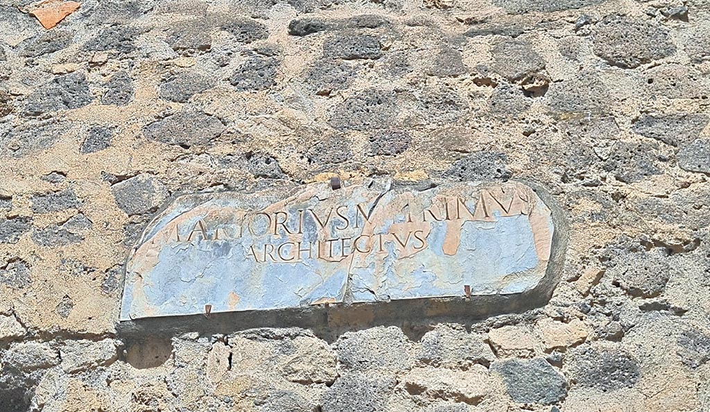 VIII.7.21 Pompeii. September 2024. Reproduction plaque on wall between theatres. Photo courtesy of Giuseppe Ciaramella.