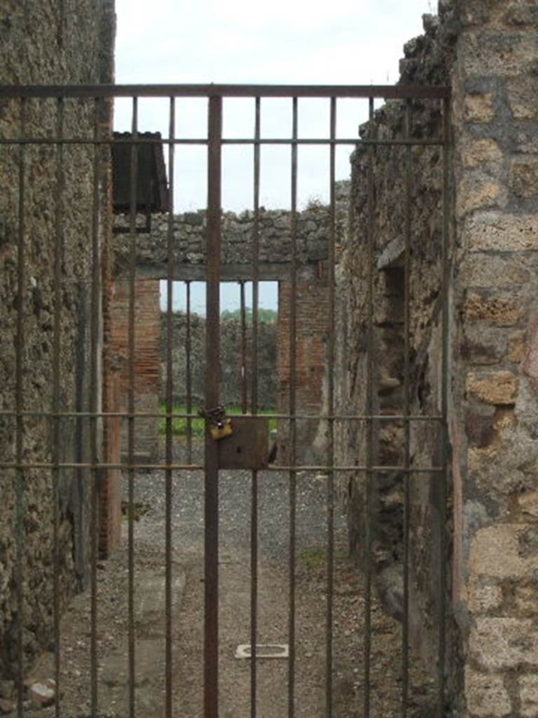 IX.2.26 Pompeii. May 2005. Entrance doorway, looking south.
According to Trendelenberg, “The second entrance of the north vicolo gave entrance to a house (G. d. s. XIII p. 33 following), which was remarkable for the good conservation of the painted plaster of which the walls of both the external and the internal façade were coated with. In the beautiful white, yellow and black decoration, we could have seen cupids, birds, animals, griffins and other fantastic figures, but in this house we would seek in vain for mythological scenes. Among the figures which enlivened the walls, a dog merited special attention. It was painted in small proportions in the first panel of the entrance corridor on the left of where one entered the doorway. It was attached by means of a chain to a tree trunk, recalling the “cave canem” mosaic at the entrance of the House of the Tragic Poet. The entrance corridor was flanked on the right by the kitchen, on the left by the triclinium that opened entirely onto the atrium. The floor of it was of mattone pesto with a meandering stripe that ran around all four sides. In the centre was a square with a circle of white stones to mark the position of the table.
Near to the entrance corridor wall in the atrium, a red podium could be seen. On its principal face the altar and two serpents were painted, above this was the lararium in the form of an aedicula with roof, with two small supporting columns. On the opposite side and right alongside of the tablinum, there was a brick base, the surface of which was all covered with rust, leaving no doubt that this was the base for the iron box, in which the money was kept. In the floor of the second room on the left was a small coloured mosaic depicting two white doves and a closed box of yellow and red below them. In the garden was a narrow terrace, supported by four stuccoed columns, on which numerous inscribed graffiti were seen, published by Baron in G.d.s, XI, p.281, then in CIL IV, p.XVII, no.3297 and following. Today, the strokes of the letters are too deleted, and are best compared with the publication. Where, however, I managed to read a few words I found exactly as copied by Baron, except the beginning of the verse of the Aeneid, which is written just like this : CERTE HINC ROMANOS, etc."
See, Trendelenberg in BdI, 1871, p.179, 
