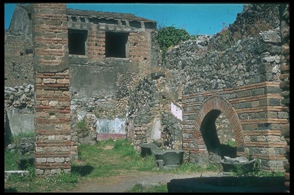 IX.3.12 Pompeii. Looking north-east from entrance. Photographed 1970-79 by G�nther Einhorn, picture courtesy of his son Ralf Einhorn. According to Boyce and Frohlich, the large rectangular pilaster opposite the oven used to be decorated with white stucco to a height of about two metres. See Boyce G. K., 1937. Corpus of the Lararia of Pompeii. Rome: MAAR 14. (p. 83 and pl. 20). See Fr�hlich, T., 1991. Lararien und Fassadenbilder in den Vesuvst�dten. Mainz: von Zabern. (p. 295 and Taf. 45.2)