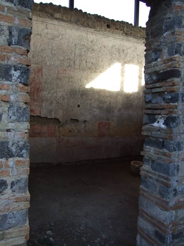 IX.5.11 Pompeii. December 2007. Doorway to room 4, looking east. This room also had a decoration of red and yellow panels, fragmented by ornate architecture. In the yellow panels were small paintings. The one on the north wall (0.51 x 0.44) showed a naked standing Bacchus, crowned with foliage, leaning on a pilaster with his left elbow, inside his elbow was his cloak. In his right hand was a short rod/staff, near to him on the ground was an amphora with a wide neck. Of the other two paintings on the east wall, the first (0.45 x 0.53) showed a Cupid, with two whips, one in each hand following a goat. The second (0.45 x 0.42) also showed a Cupid encouraging a dog to attack a rabbit. The west wall having been holed did not preserve any paintings in its panels. 
Whereas on the south, under the window, the yellow plaster that one sees above a most antique decoration (II Style) was decayed. White lozenges (diamonds) were in the red panels, in each lozenge was a painted Cupid, some with rod and pan-pipe, some with crook or with a cornucopia. In the panel of the frieze, finishing above of an elegant cornice of stucco, were painted some isolated figures, around 0.54 high. 
Beginning from the north wall, one had -
1.)  Female standing woman, with long purple robe.
2.)  Satyr crowned with reed, with greenish cloak, having a torch in his right hand and a bunch of grapes in his left hand. 
3.)  Female figure with green robe, with left hand raised to her head and holding the edge of her cloak.
4.)  Female figure with purple robe, with a garland of leaves between her hands.
5.)  Naked Satyr, with cloak around his legs, the shepherd�s crook in his left hand, and pan-pipe in his right.
6.)  Female figure dressed in dark green robe with a yellow tunic above, holding a lance in the left hand.
7.)  Another female figure with red robe and yellowish cloak, who had a fan in the guise of a leaf in her right hand.
8.)  Virile naked figure, except for a purple cloak that fell from his shoulders and which was wrapped around his left arm, in his right hand he held an  arrow tied to a snare, whose other end he held in his left hand.
9.)  Virile figure, badly preserved, with dark green cloak and a lance.
10.) Woman with green robe, gazing intently into a round mirror held in her left hand: the mirror did not have a long handle, but was held on the wrong  side.
11.) Another woman with a yellow robe and greenish cloak, who held a basket filled with fruit in both hands.
See Notizie degli Scavi, 1877, (p.248-9)
See BdI, 1879, (p.198-201)
