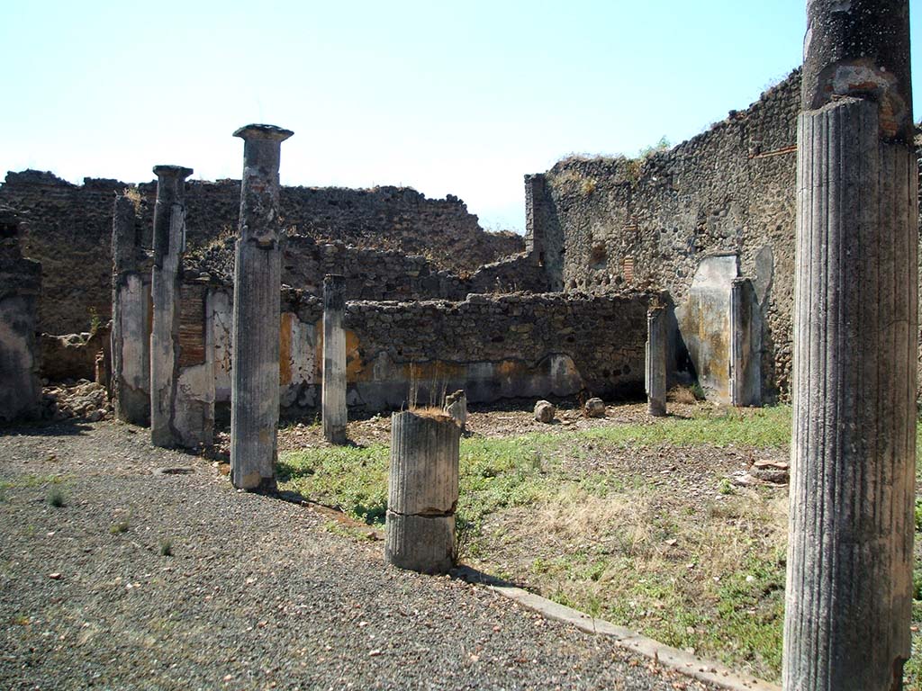 IX.5.14 Pompeii. May 2005. Looking south-west across portico of two-sided peristyle �k�.
According to Jashemski, the portico of the garden was entered directly from the atrium. There was no tablinum.
The portico was supported by four white stuccoed columns on the east, and on the south by six somewhat lower columns.
The two rooms on the east, described by Eschebach as exedra or triclinia, had a good view of the garden.
See Jashemski, W. F., 1993. The Gardens of Pompeii, Volume II: Appendices. New York: Caratzas. (p.237)  
