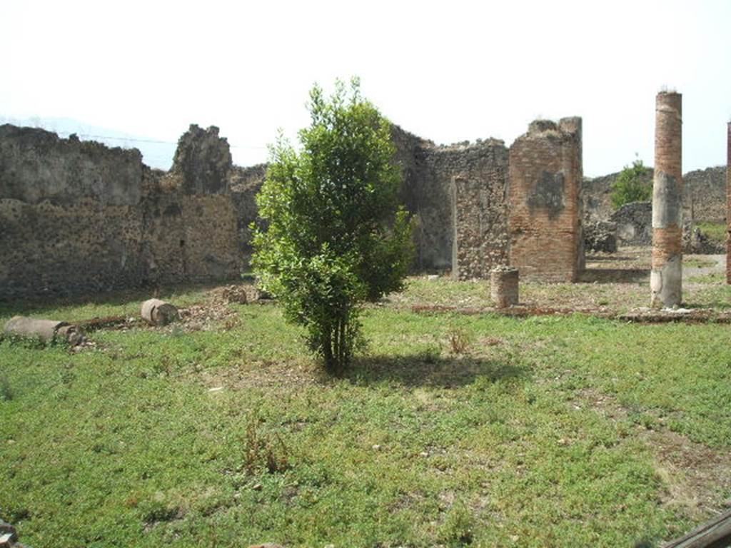 IX.6.5 Pompeii. May 2005. 
Peristyle garden area 3, looking south-west across garden area towards doorway to oecus ‘h’ (behind green plant).
The entrance doorway to the oecus, originally 3.95 wide, was made smaller by the insertion of a wall in “opus craticium” 1.50m wide, which was leaning against the brick pillar plastered in white.
The doorway to the tablinum, and westwards through the atrium to the entrance corridor is seen on the right


