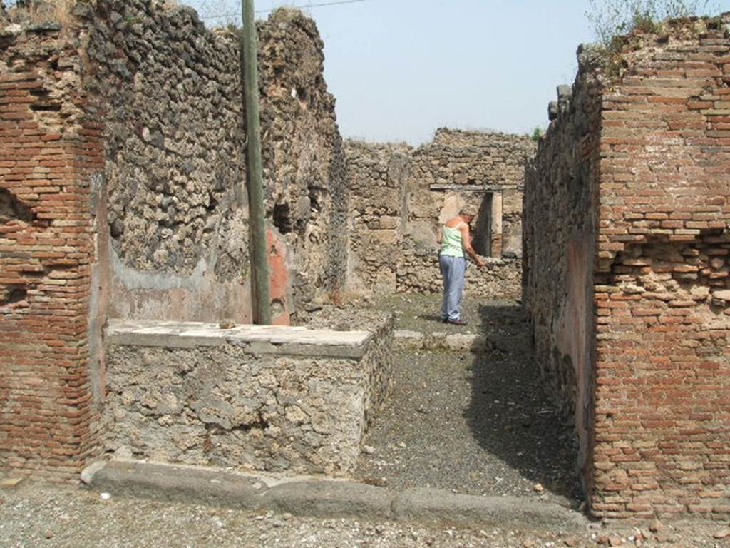 IX.6.b Pompeii. May 2005. Looking north across bar entrance. The podium of the bar/bench was decorated with fragments of marble.  According to Varone, found on the wall between entrances IX.6.a and b (on the left) were CIL IV 5203, 5204 and 5206.  He said that these vernae (slaves born into the household, appeared to be offering themselves for prices between 5 to 8 asses.  See Varone, A., 2002. Erotica Pompeiana: Love Inscriptions on the Walls of Pompeii, Rome: L�erma di Bretschneider. (p.144)
According to Epigraphik-Datenbank Clauss/Slaby (See www.manfredclauss.de), they read as -
Rogas 
verna 
(a)eris  VIII    [ CIL IV 5203]
Al[3]re 
erna  aeris  V    [CIL IV 5204]
Verna  aeris  L   [CIL IV 5206]
According to Della Corte, this bar had a sales-podium and two rooms to welcome clients. Also found on the pilaster to the left of the entrance, was the electoral recommendation - Marcus  cum  Une �..o�. (rogat)    [CIL IV 3728].  See Della Corte, M., 1965.  Case ed Abitanti di Pompei. Napoli: Fausto Fiorentino. (p.193)
According to Epigraphik-Datenbank Clauss/Slaby (See www.manfredclauss.de), this read as �
P(ublium)  Paquium  Procul(um) 
d(uumvirum)  v(iis)  a(edibus)  s(acris)  p(ublicis)  p(rocurandis)  o(ro)  v(os)  f(aciatis)  Marcus 
cum  une[3]O[3]       [CIL IV 3728]
 According to Sogliano, found on the red plastered sales-podium was a very clumsily painted hunt scene, which had nearly all vanished when found. Here could be seen a horse fleeing to the left being bitten on the side by a tiger. Underneath this, was an ox, nearly disappeared (faded). More to the left, an unrecognisable animal of small proportions. 
Approximately in the upper middle, there was a deteriorating masculine figure, that struck a fleeing tiger with a lance to the right, and underneath another wild beast crouching on its back legs. 
More to the right one could have seen a deer fleeing in this direction, jumping on its back was a dog that was biting it. Underneath this even more, a tiger fleeing to the left, and in front of the deer an animal of small proportions. Not.di Scavi d. Ant, 1879, p.21 sg. See Sogliano, A., 1879. Le pitture murali campane scoverte negli anni 1867-79. Napoli: (p.138-9)
According to Mau, on the upper part of the external side of the dividing pilaster (on the right, between his no.12 and 13, and ours numbered IX.6.b and IX.6.c) a rectangle (0.92 high x 1,12 long) was found. It was divided into squares by black lines (six horizontal lines, and eight vertical) that were alternatively either white or coloured blue/purple, green and yellow. Seen under the lowest black line of the rectangle was painted the inscription (also published in Notizie degli Scavi, 1879, p.22) which read �
IVDICIS .  AVGVSTI . P . P. ET . POPPAEAE . AVG . FELICITER .
Under the pilaster, a masonry seat was made covered with red stucco. It was not clear whether the seat or the inscription belonged to one or the other of the adjacent shops.
See also Mau in BdI 1881, (p.30-2)
