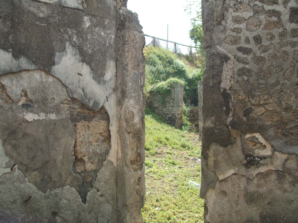 IX.6.g Pompeii. May 2005. Looking south-east across atrium, from doorway in south wall of oecus “c”. 
Looking towards doorway to room “h” in south-east corner of atrium.
According to Schefold, a painted medallion of the head of Aphrodite and Ares? was found in this oecus.
See Schefold, K., 1962. Vergessenes Pompeji. Bern: Francke. (p. 137, Taf 180,1)
According to Mau, the walls of this room were painted in the IV style on a white background, and in the middle compartments of the left and right walls were two painted medallions (0,27 diameter).
Seen on the left wall (west) was a painted head of a woman turning to the left with a serious and thoughtful expression.
Over her right shoulder, the head of a young boy (cupid?) who was looking in the same direction as her.
Seen on the right wall (east) was a painted head crowned with foliage (?Bacchus) which has nearly vanished.
The middle compartment of the north wall was occupied by a window.
In each of the side compartments of the side walls and in the rear (north) was seen a flying cupid, turning always towards the centre of the wall.
On the left wall, to the left  – playing the lyre.
On the left wall, to the right  – carrying two flutes in the right hand, and a lowered tambourine in the left hand.
On the rear wall, to the left  – carrying a green object but not clear, it could have seemed like a quiver, but it had at the top – towards where it thinned – something pointed. A red ribbon was attached. 
On the rear wall, to the right  – holding an object, completely vanished, in a raised hand towards the left.
On the right wall, to the left  – carrying a small, low basket with a handle in the left hand and a ribbon lowered in the right hand.
On the right wall, to the right – holding a shepherd’s crook in the left hand, and pan-pipes in the right hand.
They were 0,24 high, naked outside of a green flying robe in the guise of a shawl.
See Bullettino dell’Instituto di Corrispondenza Archeologica (DAIR), 1880, p. 268-9.
