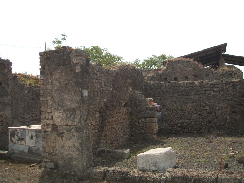 IX.7.23 Pompeii. May 2005. Looking south to entrance.
On the left of the photo, against the east wall was the site of the stairs to the upper floor, above the remaining stone step.
According to Mau, the stairs would seem to have been made of wood other than the lower stone one.
On the left was also the site of the latrine, originally hidden by a thin wall.

