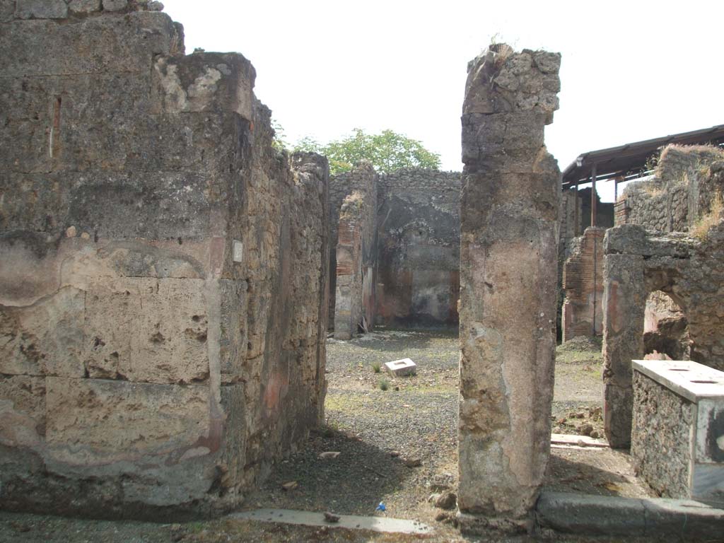 IX.7.25 Pompeii. May 2005. Looking south along fauces or entrance corridor “1”, in centre, and IX.7.24, Room “a”, on the right.
According to Mau, the doorway was capable of being closed in the evening by a beam slotted into the slits in the walls of the corridor on either side .
Another beam or girder would have leaned obliquely against the door and against the notched stone sunk into the flooring of the entrance corridor, at a distance of 1.70m from the lava threshold of the doorway.
The flooring of the corridor and the atrium was made from opus signinum made from crushed lava (lavapesto), instead of crushed brick or tile (cocciopesto).
The walls of the fauces, and the atrium were painted with a red background.
See Mau, in Bullettino dell’Instituto di Corrispondenza Archeologica (DAIR), 1882 (p.177-8)
