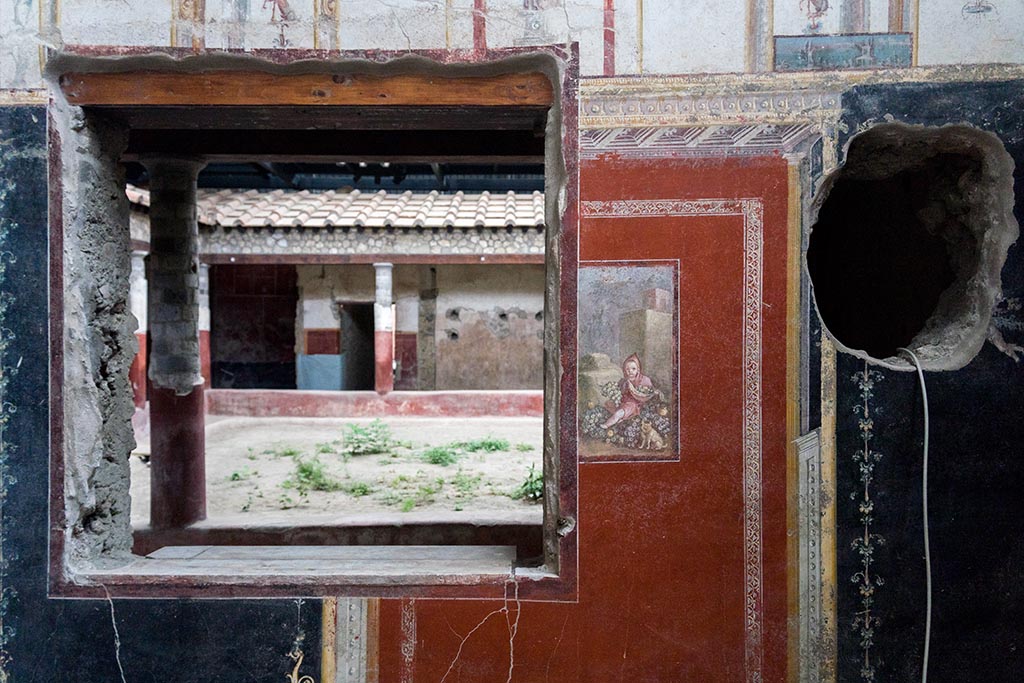 IX.12.A/IX.12.9 Pompeii. July 2024. Room 18, east wall with window to garden area. Photo courtesy of Johannes Eber.
The window on the east wall (1.50 m x 1.54 m high) opens onto the three-sided portico offering a view of the viridarium.
The opening preserves the marble sill slab, between 3 and 4 cm thick, and some iron elements still in situ attributable to the hinges. 
See E-Journal 14, 24.05.24 Regio IX, 12: Insula dei Casti Amanti, Casa dei Pittori al lavoro, Ambiente 18: nota preliminare, p. 6, fig. 12.


