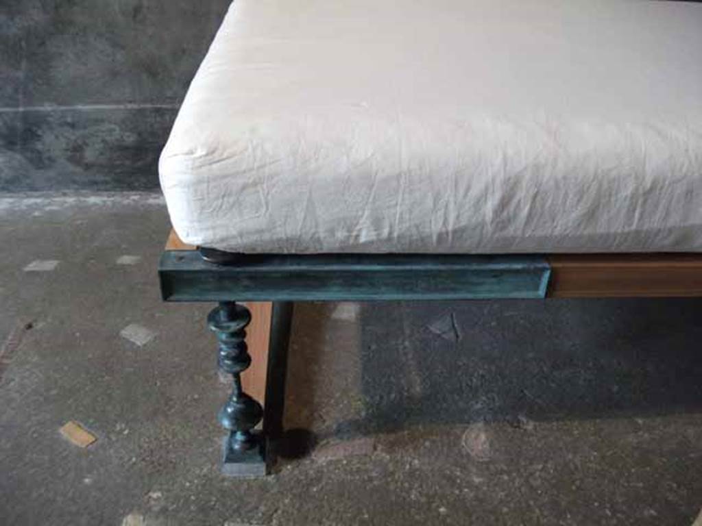 IX.13.1-3 Pompeii. May 2010.  Room 13, reproduction couch with metal leg.