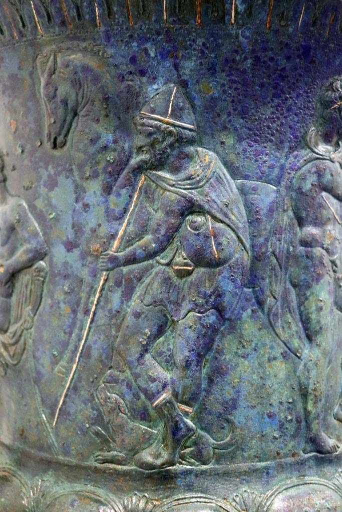 IX.13.1-3 Pompeii. February 2021. 
Bronze krater with scenes in relief, found in triclinium, on display in Antiquarium, VIII.1.4.
Detail of the bearded figure holding a staff. Photo courtesy of Fabien Bièvre-Perrin (CC BY-NC-SA).
