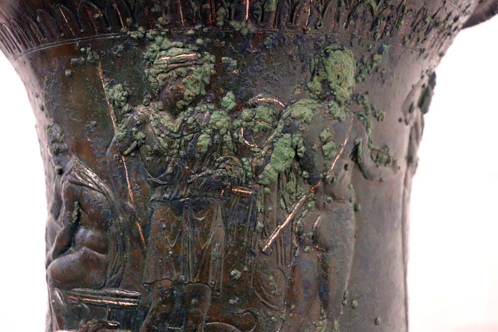 IX.13.1-3 Pompeii. February 2021. 
Detail from bronze krater with scenes in relief, found in triclinium, on display in Antiquarium, VIII.1.4.
Two of the other standing armed male figures.  Photo courtesy of Fabien Bièvre-Perrin (CC BY-NC-SA).
