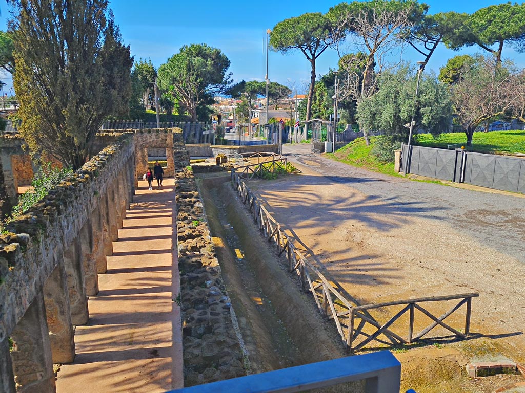 HGW24 Pompeii. Villa of Diomedes. March 2024. Looking south along north portico, on left, from upper terrace.  
The area of the original carriage entrance to Pompeii in the 1800’s, can be seen on the right. Photo courtesy of Giuseppe Ciaramella.
