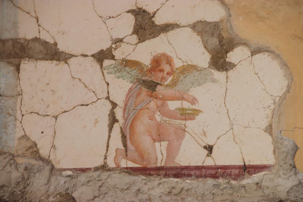 Villa San Marco, Stabiae, October 2022.
Room 30, painting of kneeling Eros holding a dish, from east wall above doorway to room 50, in north-east corner.
Photo courtesy of Klaus Heese.