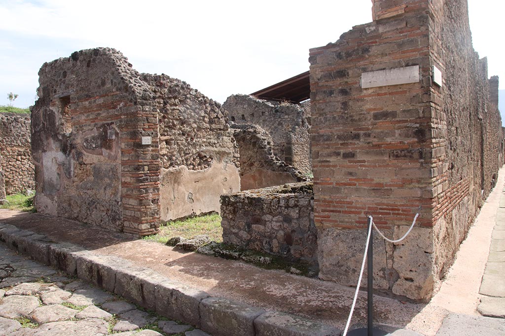 Unnamed vicolo (continuation of Via degli Augustali), Pompeii, south side, on left. October 2024. 
Looking south-east to entrance doorway of IX.7.22, on corner with Vicolo di Tesmo, on right. Photo courtesy of Klaus Heese.
