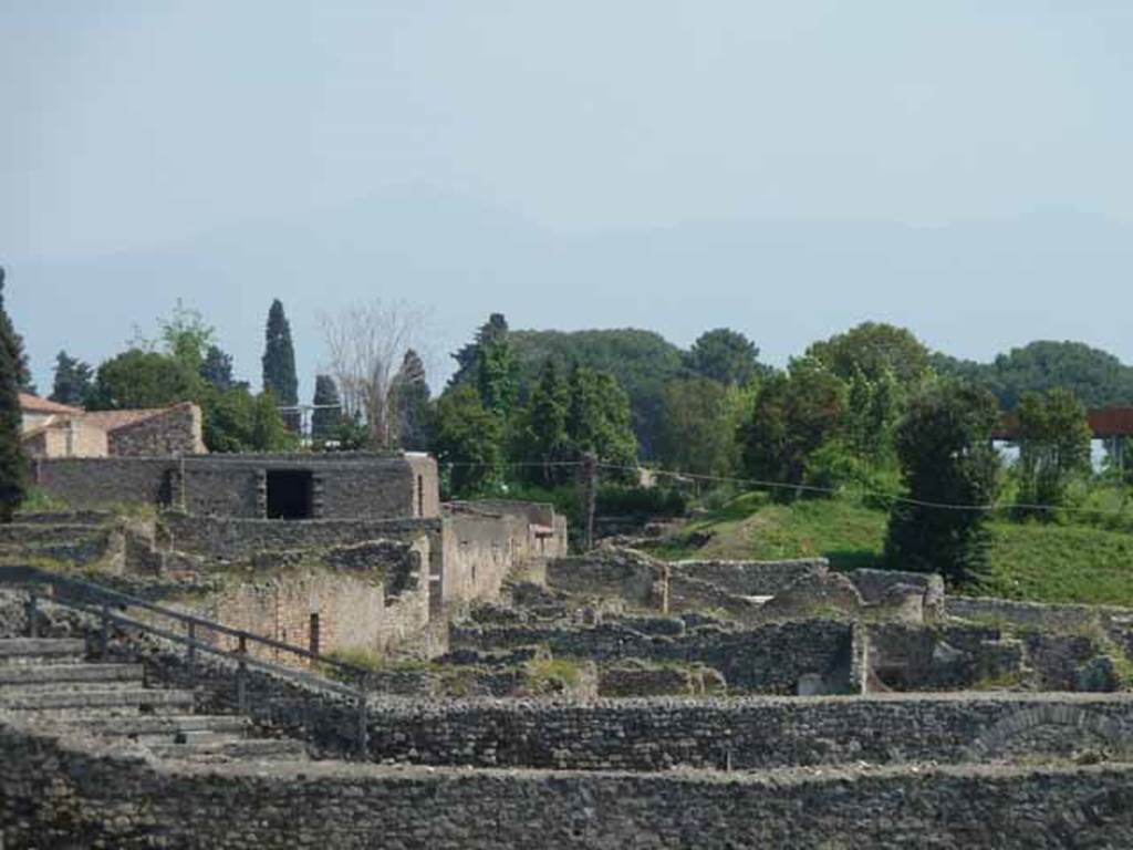 Unnamed vicolo between I.3 and I.2. May 2010. Looking east from the Triangular Forum. Behind the seating of the small theatre can be seen the vicolo, with the south wall of 1.3 and the south wall of the insula of Menander visible, on the left.