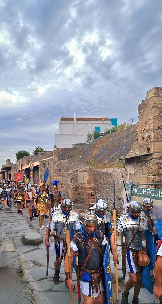 Via dell’Abbondanza, north side. 28th September 2024. 
Roman Legionary re-enactors marching in Pompeii. 
Looking west towards IX.11, in centre, during “Ludi Pompeiani” event. 
Photo courtesy of Giuseppe Ciaramella.

