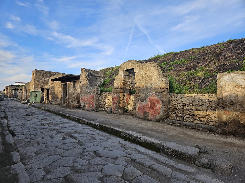 Via dell’Abbondanza. November 2024. 
Looking west along III.5 on north side of roadway, towards III.4 on left behind green hut. Photo courtesy of Annette Haug. 
