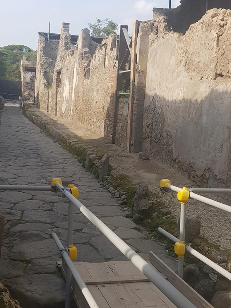 Vicolo dei Balconi, Pompeii. October 2022. 
Looking north along east side of roadway. Photo courtesy of Klaus Heese.
The house entrances (now blocked) we number as B5, B4 and B3. The balcony of B1 is at the junction but B2 is not visible in this photo.

