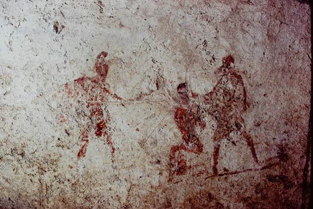 Santa Maria Capua Vetere, Mithraeum. 1974. Initiation painting located on front of benches. 
Photo by Stanley A. Jashemski.   
Source: The Wilhelmina and Stanley A. Jashemski archive in the University of Maryland Library, Special Collections (See collection page) and made available under the Creative Commons Attribution-Non Commercial License v.4. See Licence and use details.
J74f0583
According to Minto, the initiate is shown seated, with hands tied behind his back and his eyes bandaged. On the right, dressed in a white tunic, is the mystagogus, the teacher who has prepared the initiate for entry to the cult. On the left is a priest in an oriental costume and wearing a Phrygian cap and carries a sword in his hand.
See Notizie degli Scavi di Antichità, 1924 p. 369, fig. 11.

