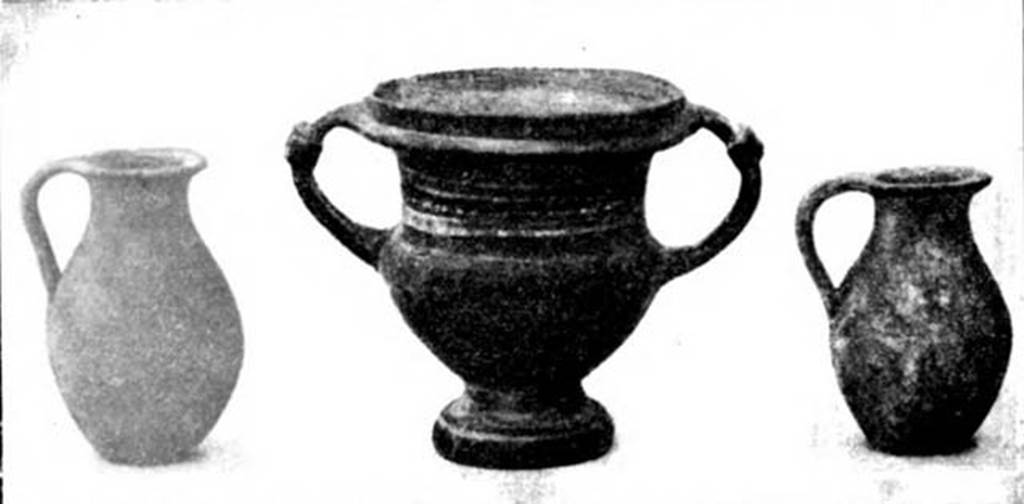 Pompeii Fondo Azzolini. Samnite Tomb III. 
Three of the four vases found to the left of the skull.
Left is a small single handled jug, found inside the olla. 
Right is another similar single handled jug. 
Centre is a krater covered in shiny black varnish, decorated with a row of white dots between two bands, all running round between the two handles.
See Notizie degli Scavi di Antichità, 1911, p. 110, fig. 5).
