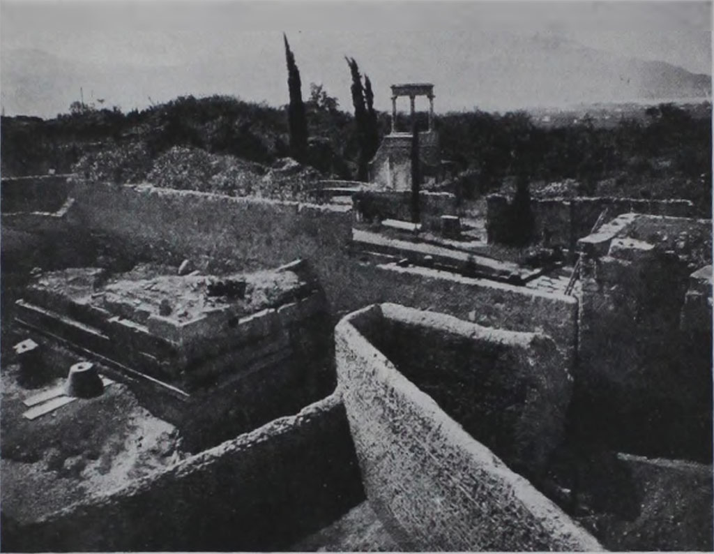 HGE04 Pompeii. 1933-5. View of rear of tomb during excavations showing also the cone found by Maiuri.
According to Kockel in 1933/35, A. Maiuri excavated the entire area between the city wall and the Villa delle Colonne a mosaico, completely exposing North 4 as well. 
To the north of the base he found a cone and a Corinthian capital to match.
See Kockel V., 1983. Die Grabbauten vor dem Herkulaner Tor in Pompeji. Mainz: von Zabern, p. 122. 
See Notizie degli Scavi di Antichit�, 1943, p. 301, fig. 17.

