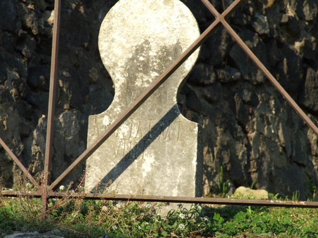 Pompeii. December 2006. Columella found in situ at front of HGE42.
This columella has the inscription
ARRIAE M L 
VTILI.

According to Epigraphik-Datenbank Clauss/Slaby (See www.manfredclauss.de) this reads

Arriae M(arci) l(ibertae)
Utili       [CIL X 1044]

According to Kockel it is not mentioned in the excavation reports.
He presumes it to have been found in 1774 at the same times as the marble plaques.
The back takes the form of a feminine hairstyle with a bun at the back of the head.
See Kockel V., 1983. Die Grabbauten vor dem Herkulaner Tor in Pompeji. Mainz: von Zabern. (p. 181).