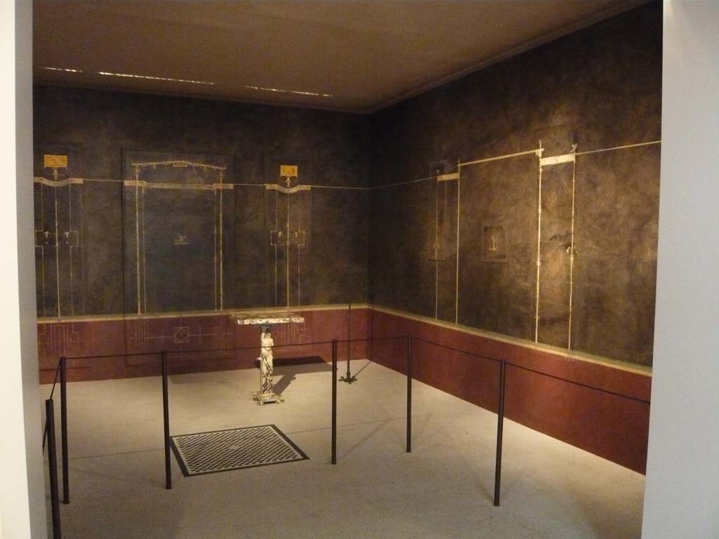 Villa of Agrippa Postumus, Boscotrecase. December 2010. Room 15, looking towards the north-east corner and east wall of cubiculum.
Photograph taken at Metropolitan Museum New York. Photo courtesy of Buzz Ferebee. 
According to NdS, 
“Room “No. 15”, the first cubiculum, had a chessboard mosaic of 0.92m sides closed in a broad black band and containing a net of nine hexagons with black outlines in the centre of its floor of white mosaic: and, in the threshold was a more simple geometric black pattern. Of the elegant and sober wall decorations, on a black background above a dark-red dado/plinth, sparing a detailed description, I reproduce fig. 7 (below): 
