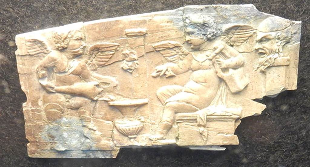 Villa Rustica di Marcus Livius Marcellus. Ivory plaque found in a cubiculum. On the right is a pilaster on which is a bearded head in relief (Silenus?).
Left and centre are two cupids, one holding a lyre and the other pouring wine from an amphora into a krater which is near a fountain with a mask on a pilaster.
Photo courtesy of Buzz Ferebee.
See Notizie degli Scavi di Antichit�, 1929, p. 185, fig. 7.
