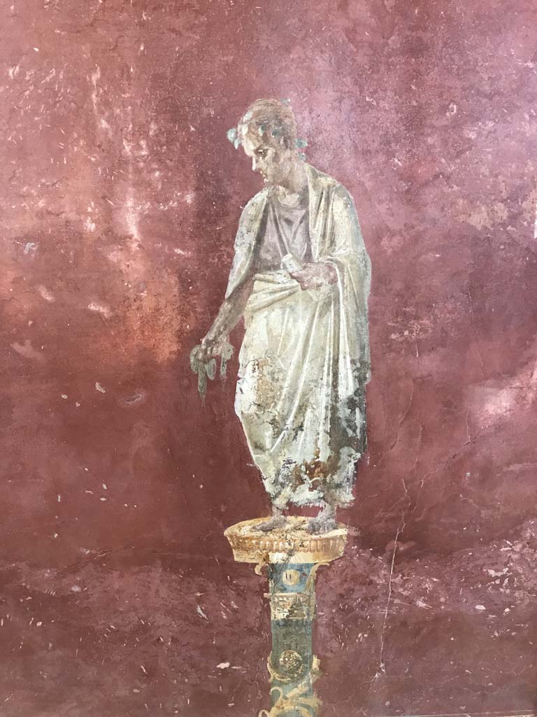 Complesso dei triclini in località Moregine a Pompei. April 2019. Triclinium C, west wall.
Robed figure with crown of leaves and holding what appears to be a scroll. A poet or philosopher?
Photo courtesy of Rick Bauer.