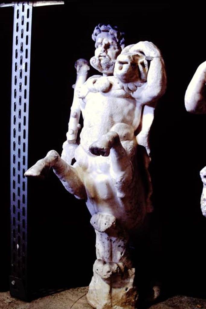 Oplontis Villa of Poppea, 1977. One of a group of four centaurs, a male holding a club with a small boar on his shoulder. 
Two centaur fountains had been on each side of the passageway.
There was no evidence of pipes, so they had not been used as fountains in their final location.
Photo by Stanley A. Jashemski.   
SAP inventory number 70068.
Source: The Wilhelmina and Stanley A. Jashemski archive in the University of Maryland Library, Special Collections (See collection page) and made available under the Creative Commons Attribution-Non Commercial License v.4. See Licence and use details.
J77f0340
According to De Caro, a group of four centaurs were found under portico 33 on 17th February 1970. 
When they were found, they were very badly damaged. Heads and limbs were mostly detached and it was necessary to provide patient and pain-staking work of re-composition. 
See De Caro, S.1976. Sculture dalla villa �di Poppea� in Oplontis (p.198) in Cronache Pompeiane, II, 1976, (p.184-225)

