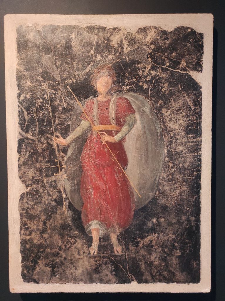 Stabiae, Villa Arianna,
Room 42, painted panel of female tibia player in red tunic with white cloak and with two pipes.
Stabia Antiquarium inv. 64190.